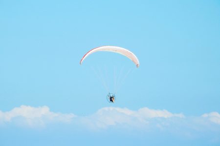 A low angle shot of a person parachuting down under the beautiful cloudy sky